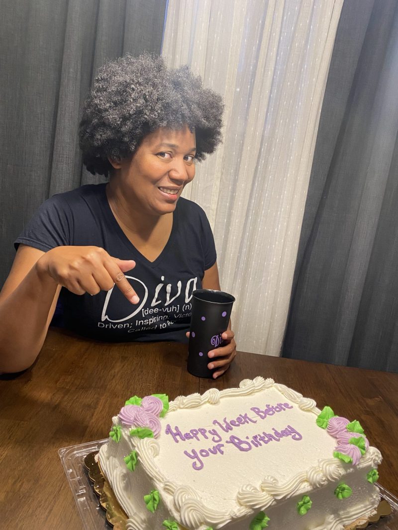 Woman smiling beside a birthday cake as part of her annual tradition to celebrate herself and reflect on personal growth