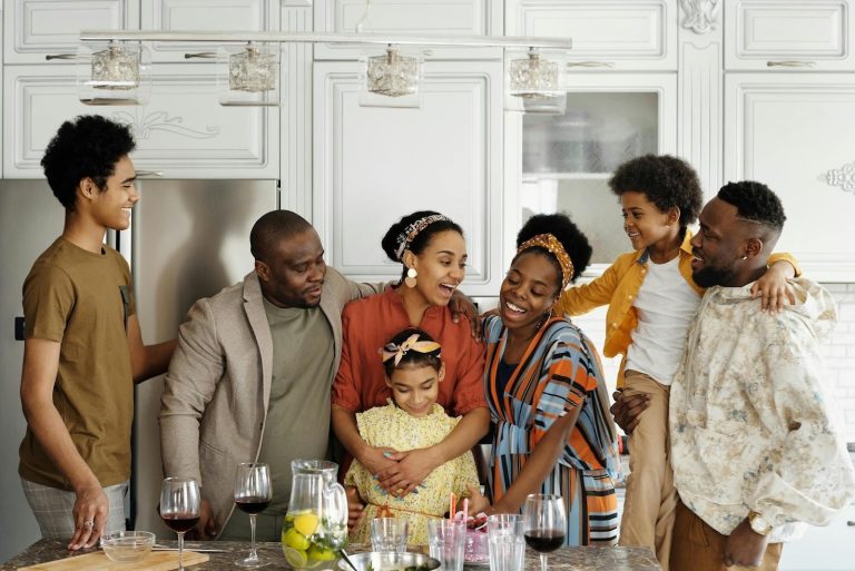 Family standing together in a kitchen, smiling and embracing while spending time together at home.