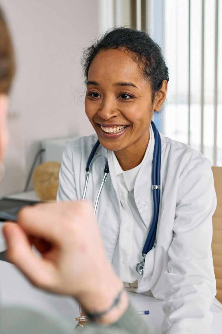 Healthcare professional smiling while speaking with a patient during a consultation.