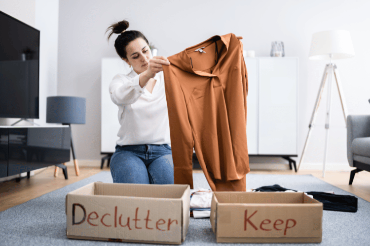 Woman sorting clothes into keep and declutter boxes in a tidy living room