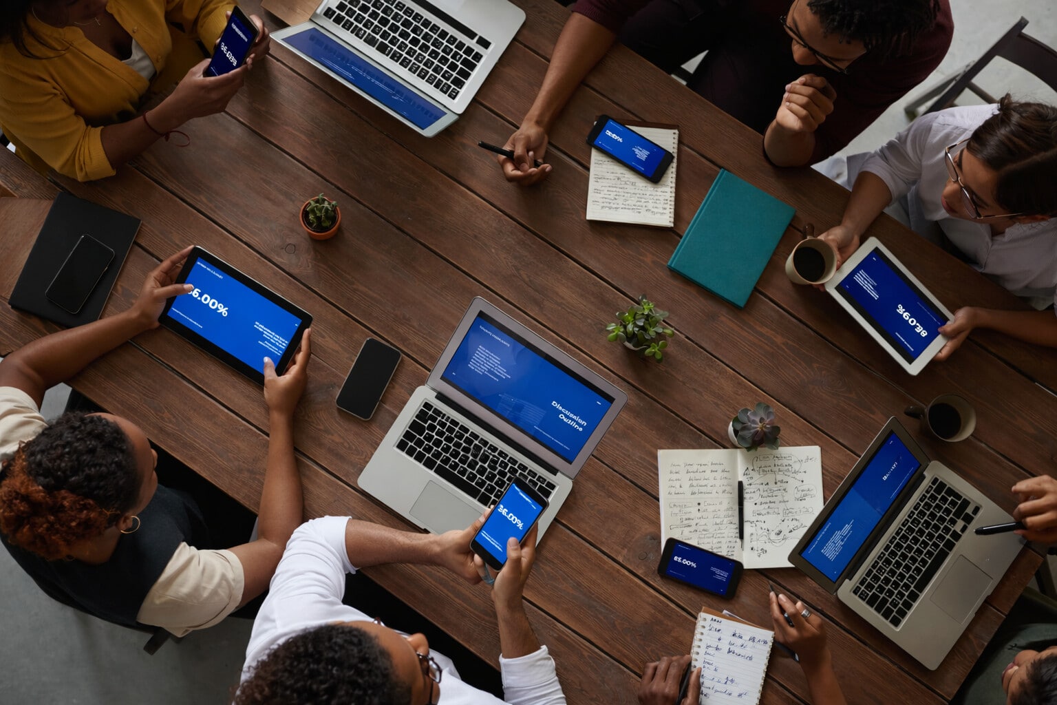 Overhead view of Black women entrepreneurs collaborating with laptops and tablets during a planning session