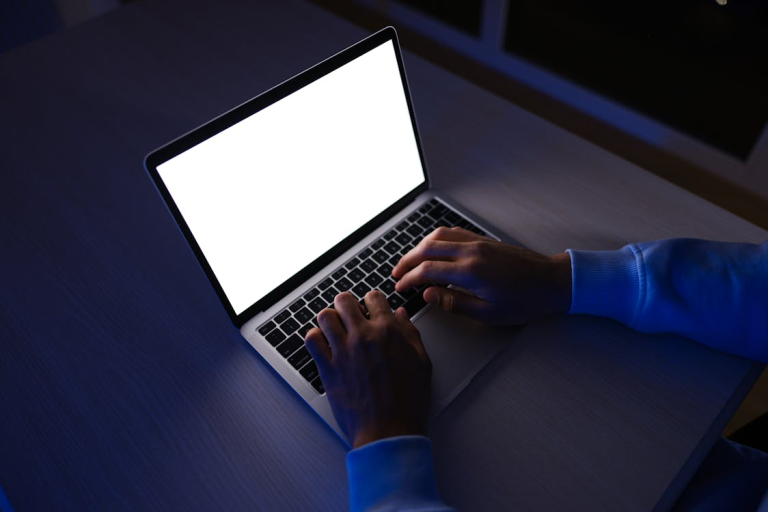 Hands typing on a laptop during cybersecurity monitoring at night