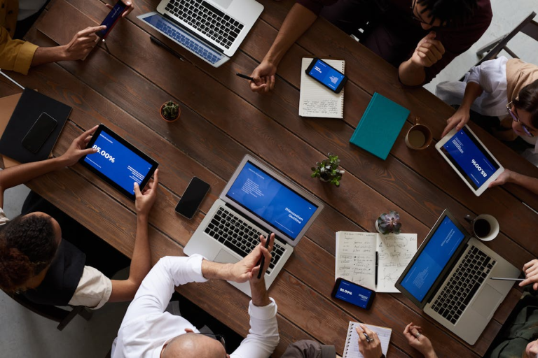 Entrepreneurs collaborating at a table while planning business strategy using laptops, tablets, and notes