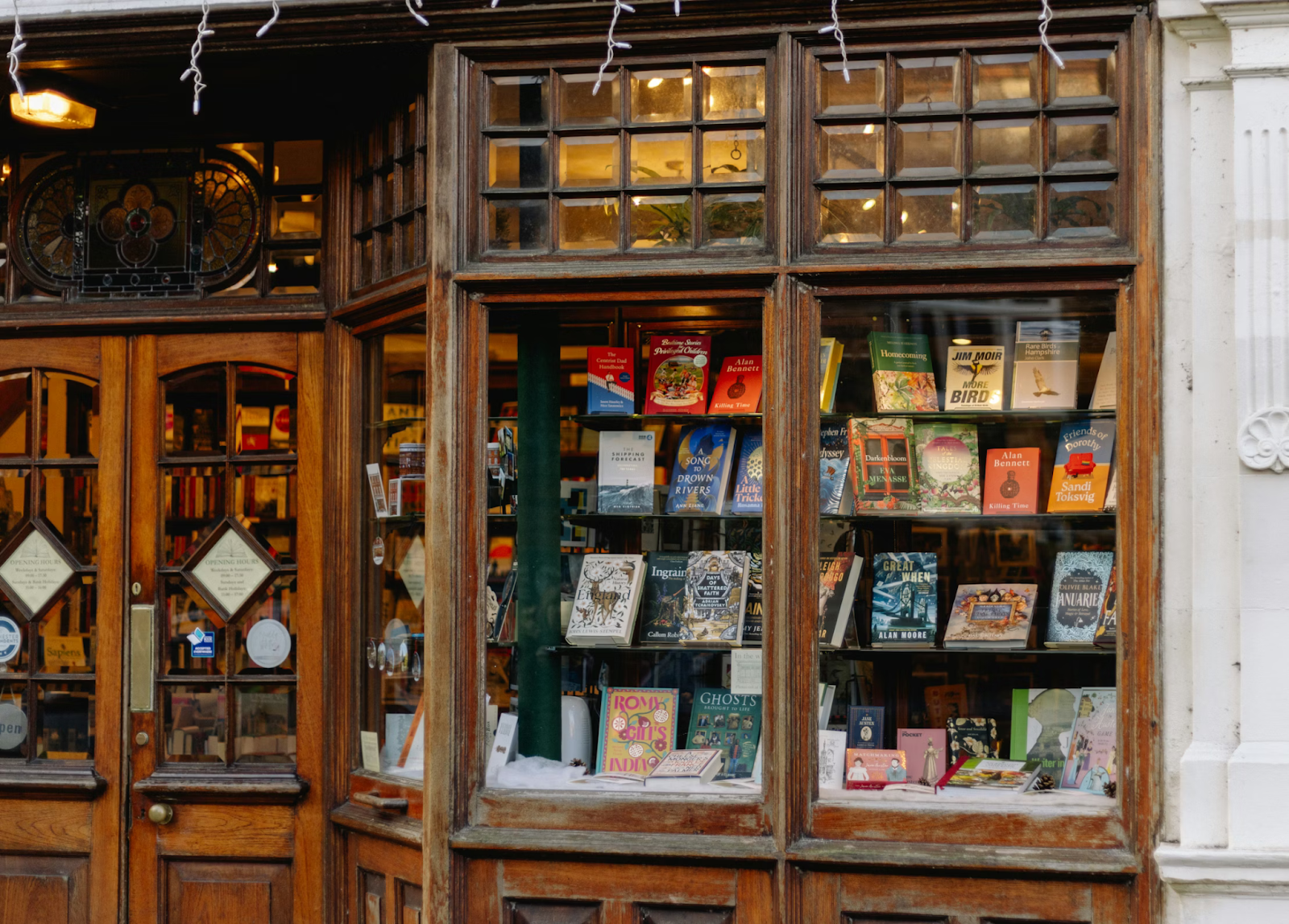 Independent bookstore window displaying a variety of books by different authors