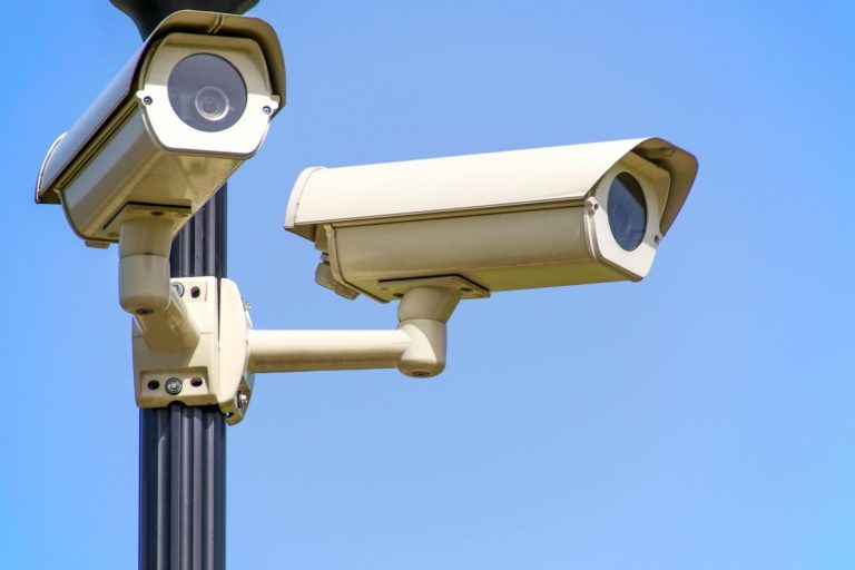 Two outdoor surveillance cameras mounted on a pole, representing business security measures and asset protection