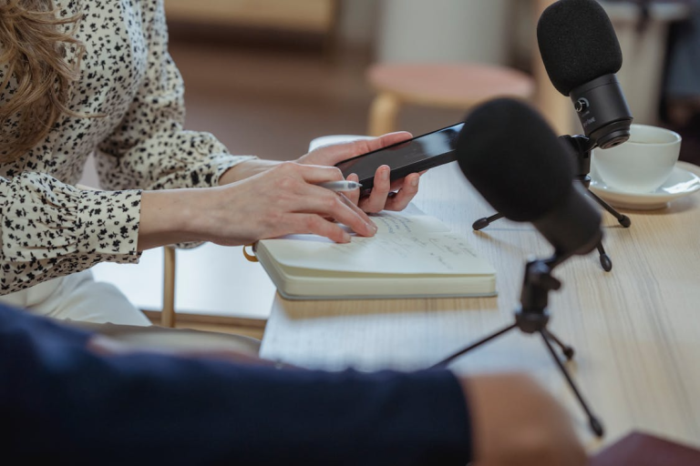 Person recording audio content while checking notes on a smartphone, highlighting how shared media can contribute to security risks