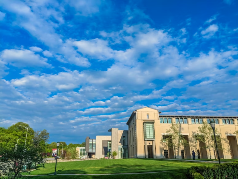 Modern university campus buildings with green lawn under a blue sky