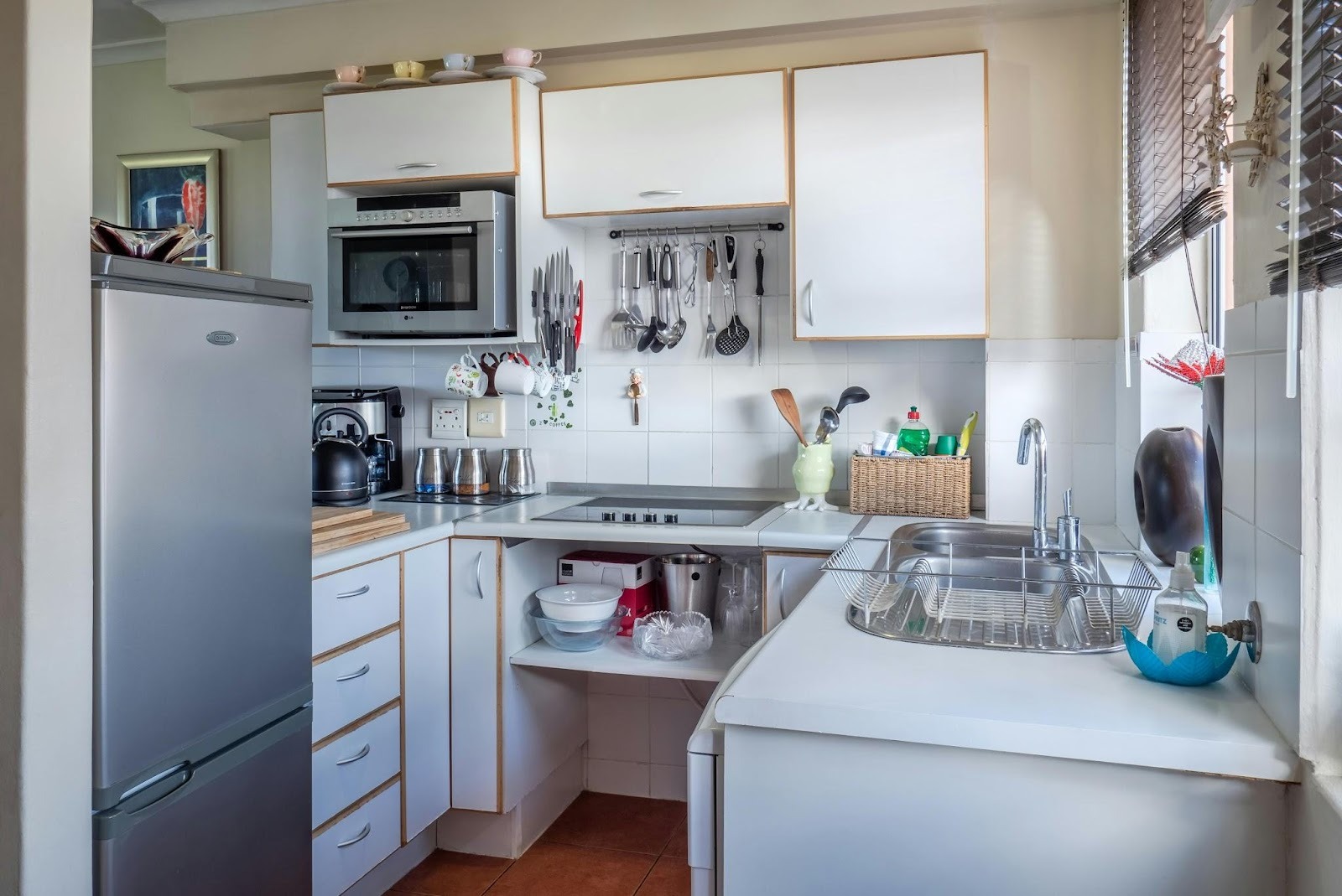 Small corner kitchen with white cabinets, sink, stove, and organized storage in a functional layout