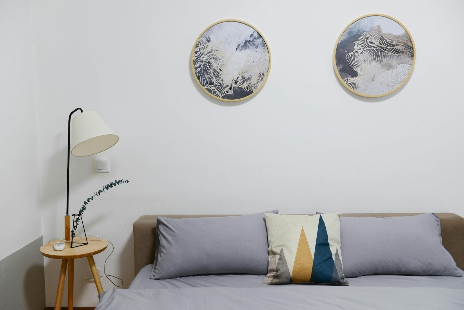 Minimalist bedroom with neutral circular wall art displayed above a bed