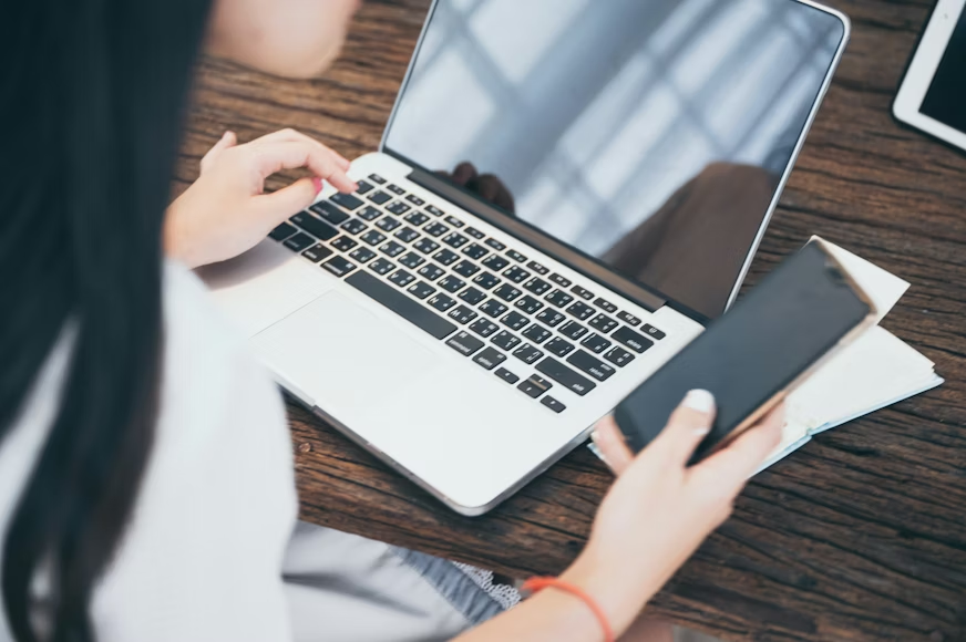 Business user managing laptop and smartphone with cybersecurity protection in place