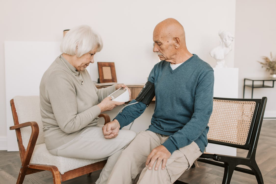 Older adult having blood pressure checked by caregiver in home care setting