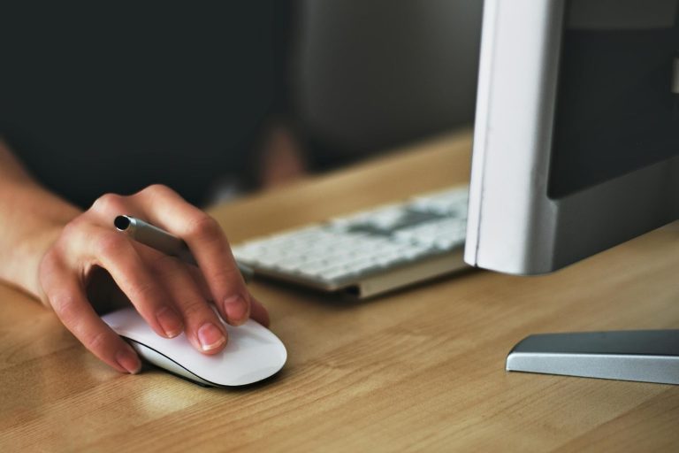 Close-up of hand using computer mouse while reviewing financial data