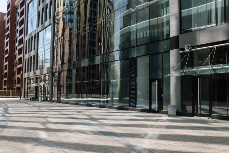 Glass-front commercial office building exterior with clean pavement and modern business entrance