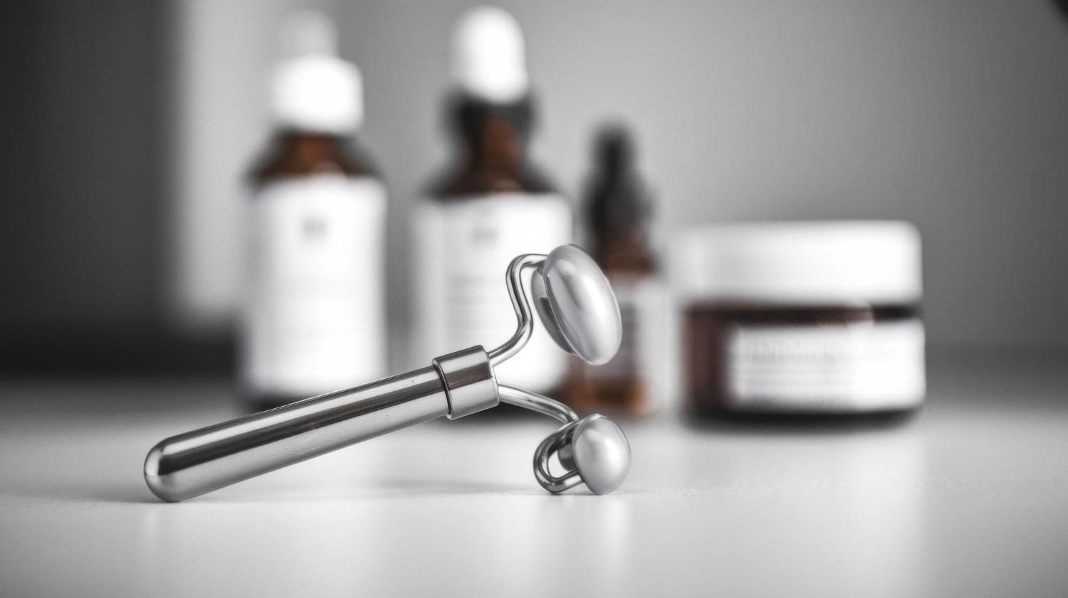 Facial roller with skincare products used in an at-home beauty routine