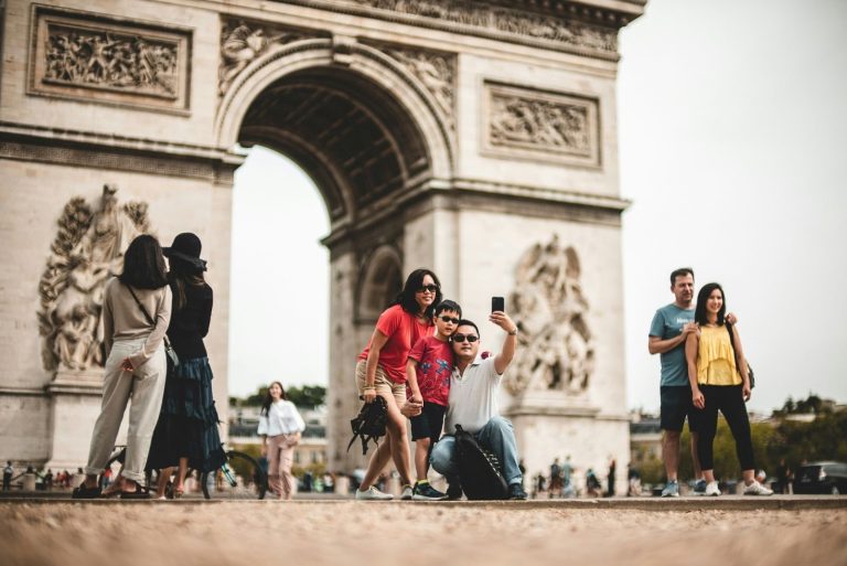 Family taking a selfie in front of the Arc de Triomphe during vacation