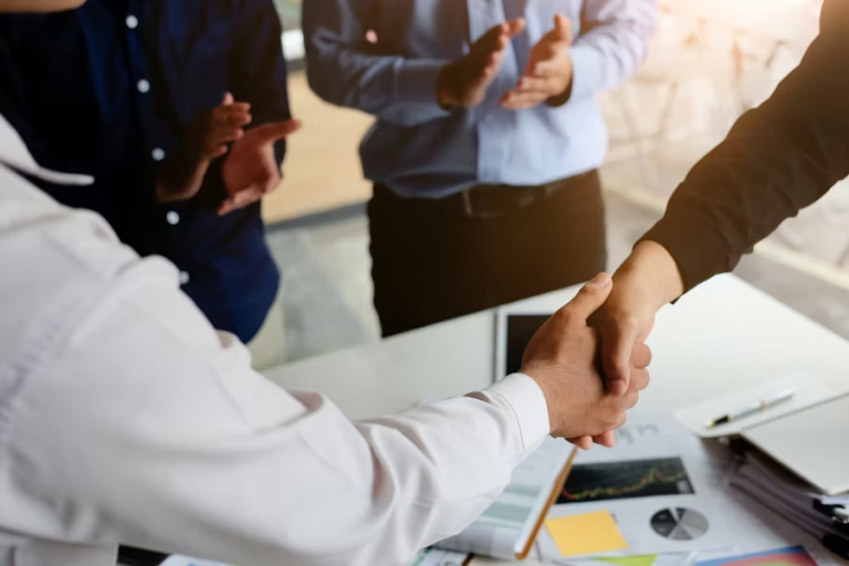 Business professionals shaking hands over desk to finalize collaboration