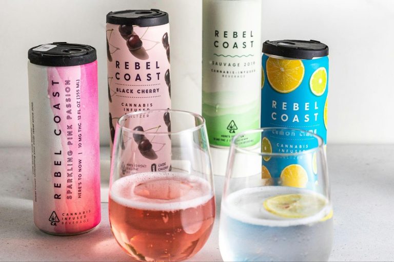 Assorted canned alternative beverages with glasses on a countertop