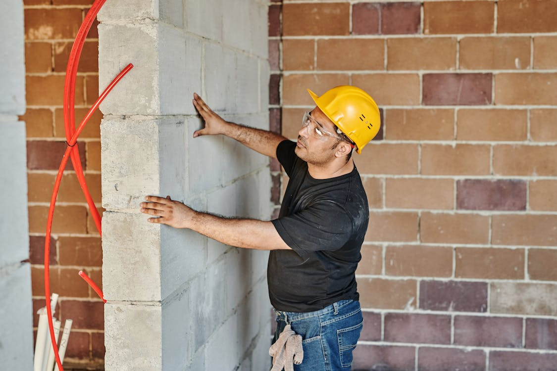 Construction worker inspecting a concrete block foundation wall during a building or renovation project