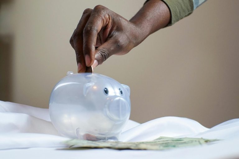 person putting coin into piggy bank representing saving and capital protection