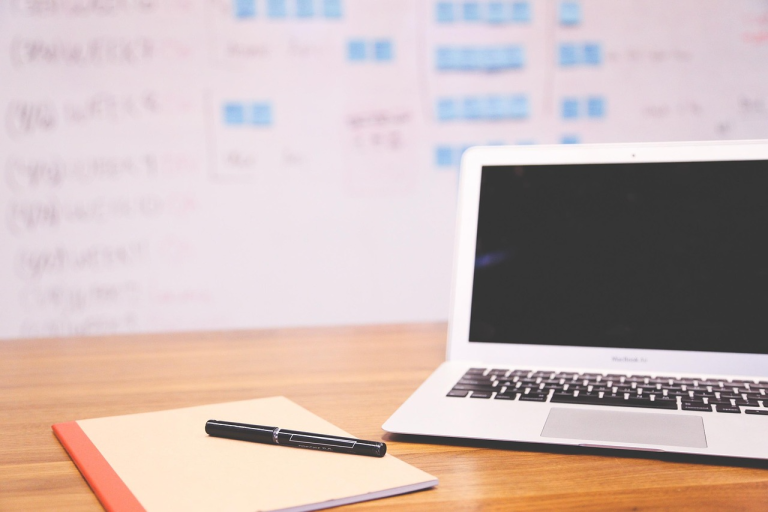 laptop and notebook on desk used for outlining a business plan