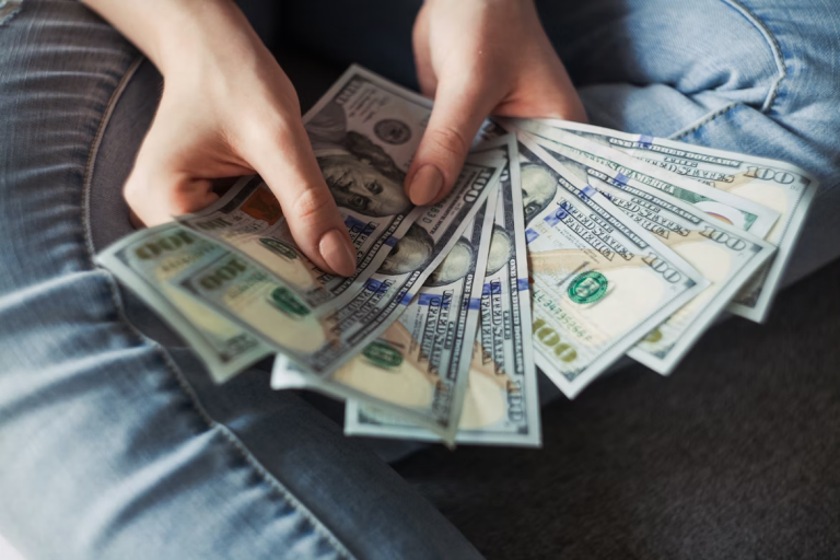 hands holding hundred dollar bills representing saving money and growing savings