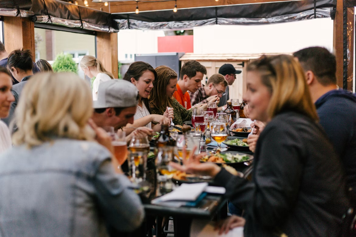 people dining together at a large gathering with food and drinks