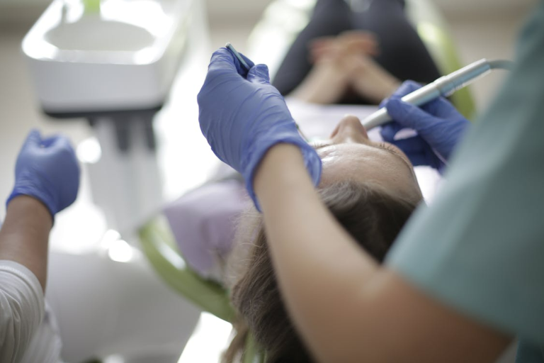 Dental professional using tools to examine a patient’s teeth