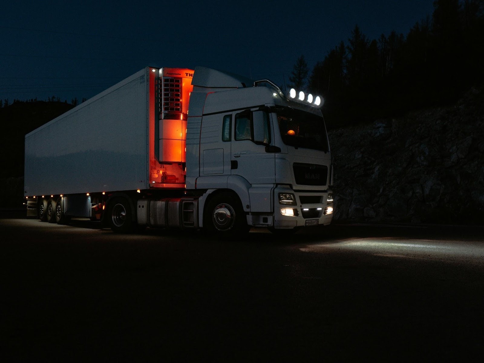 Large delivery truck driving on a highway at night with headlights on