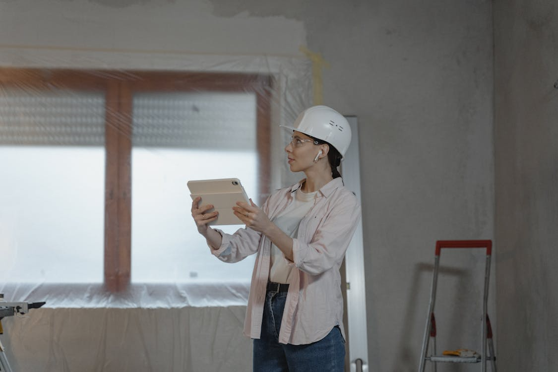 Woman contractor using a tablet while inspecting a home renovation project indoors