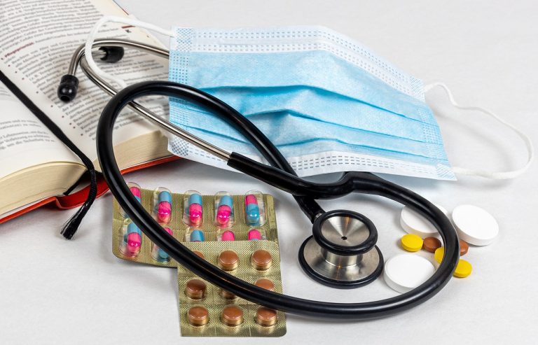 Stethoscope, face mask, and medication on a medical book