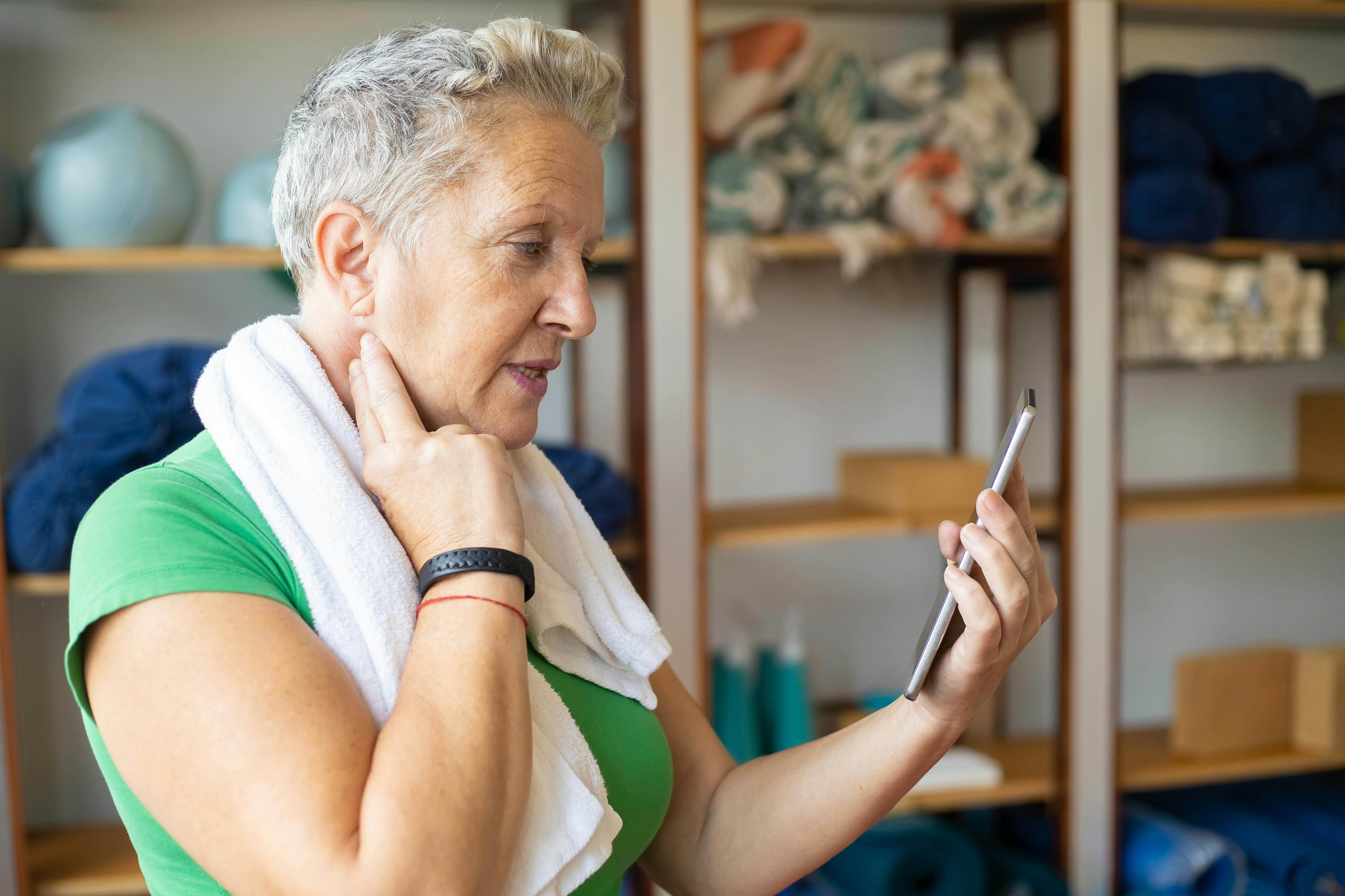 Middle aged woman in workout clothes checking health data on her smartphone