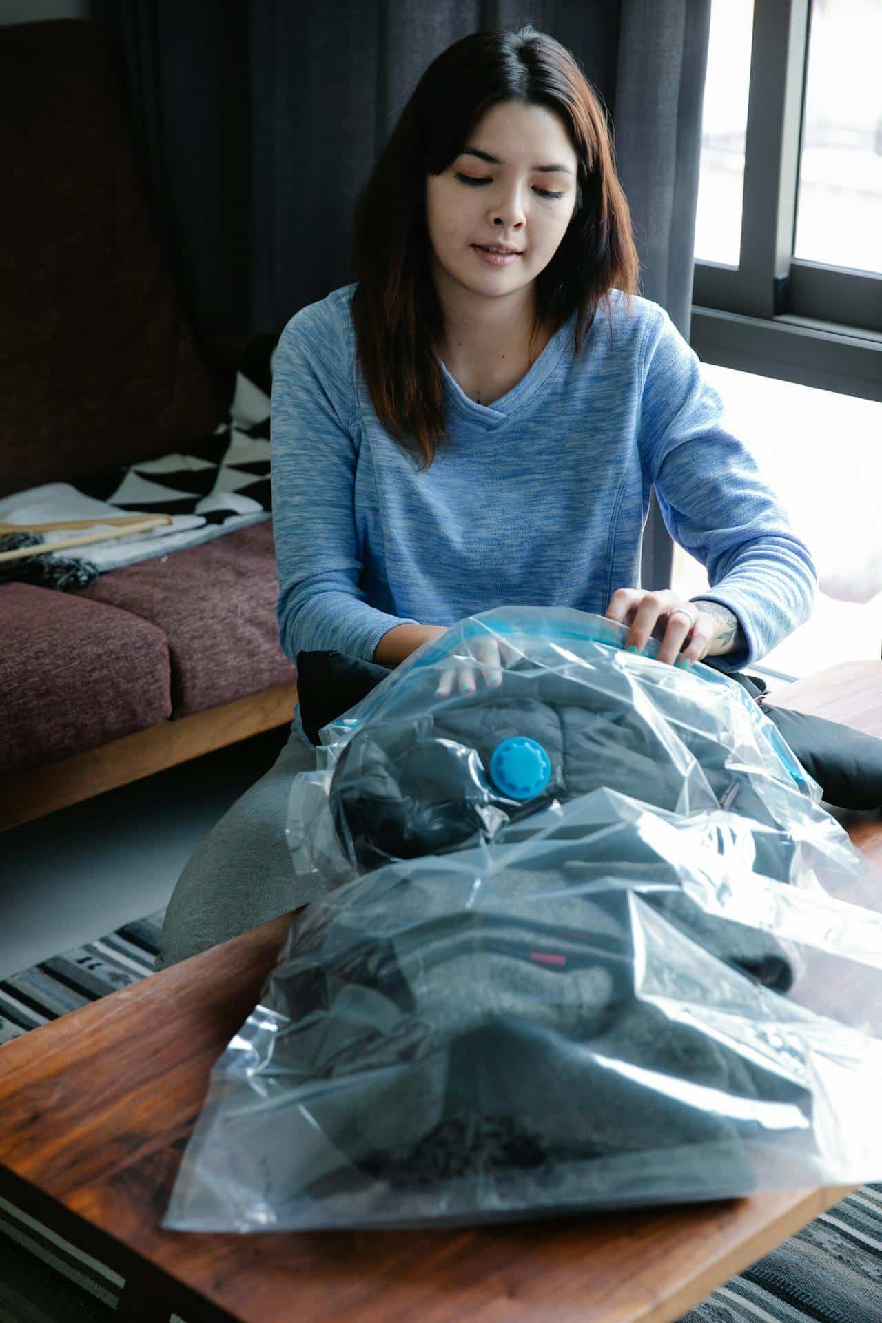 Person organizing clothes inside an open suitcase on the floor
