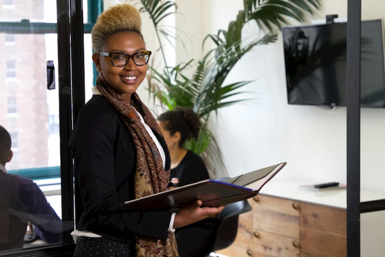 Black woman holding a notebook in a modern office workspace