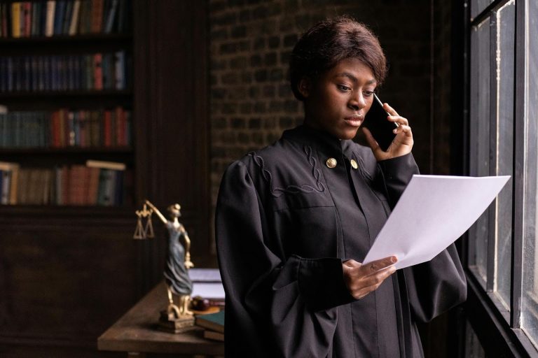 Woman in a legal office reviewing paperwork while talking on the phone near a window