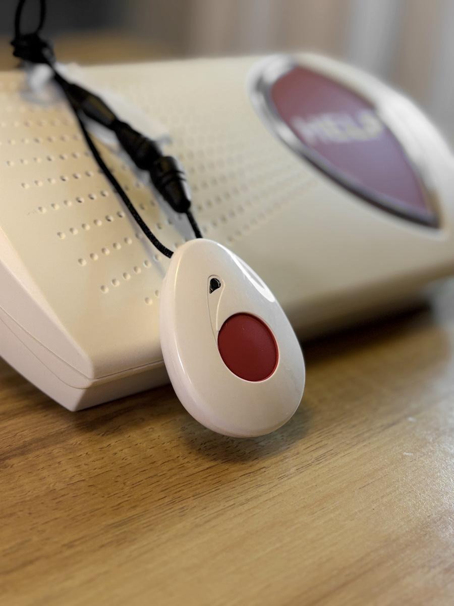 medical alert pendant with emergency button next to home base unit for senior safety