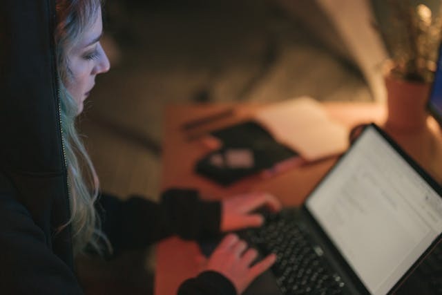 Person sitting with a laptop in a dim, quiet setting researching rehab facility options for addiction recovery
