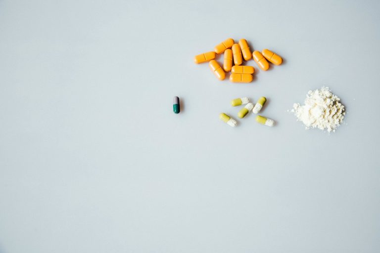 Assorted pills on a plain background representing addiction treatment and recovery decisions