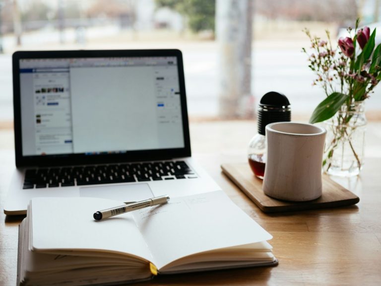 laptop and notebook on desk for AI blogging and content planning