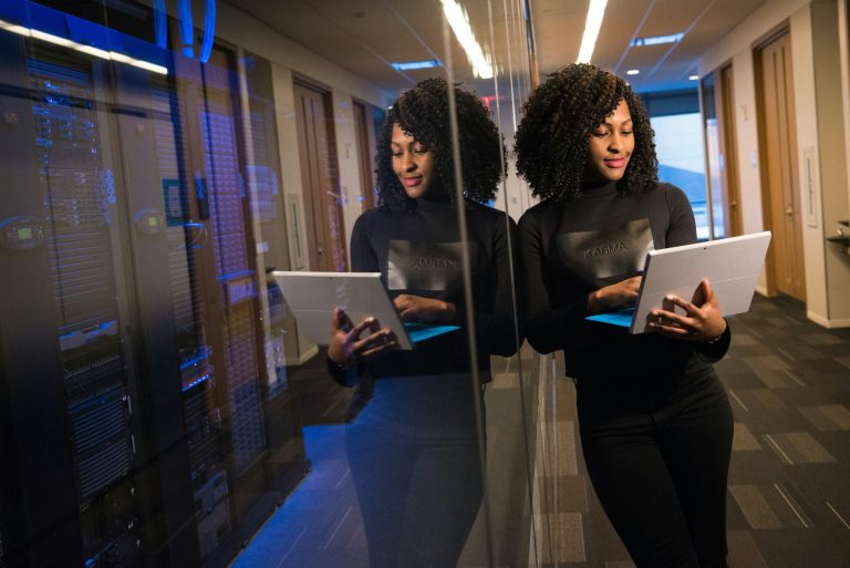 Professional woman using tablet in data center hallway representing a tech savvy business environment
