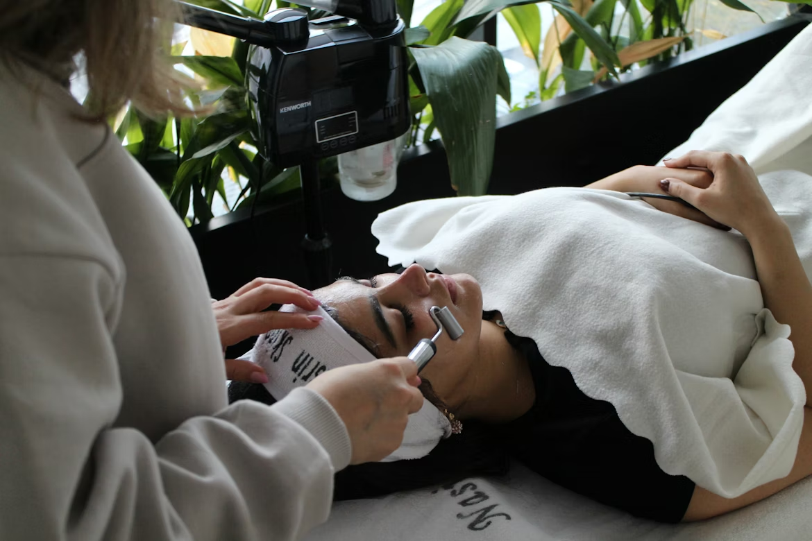 Woman receiving a facial treatment with a skincare device in a spa setting