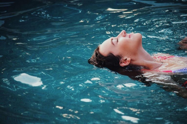 Woman floating peacefully in a swimming pool with eyes closed