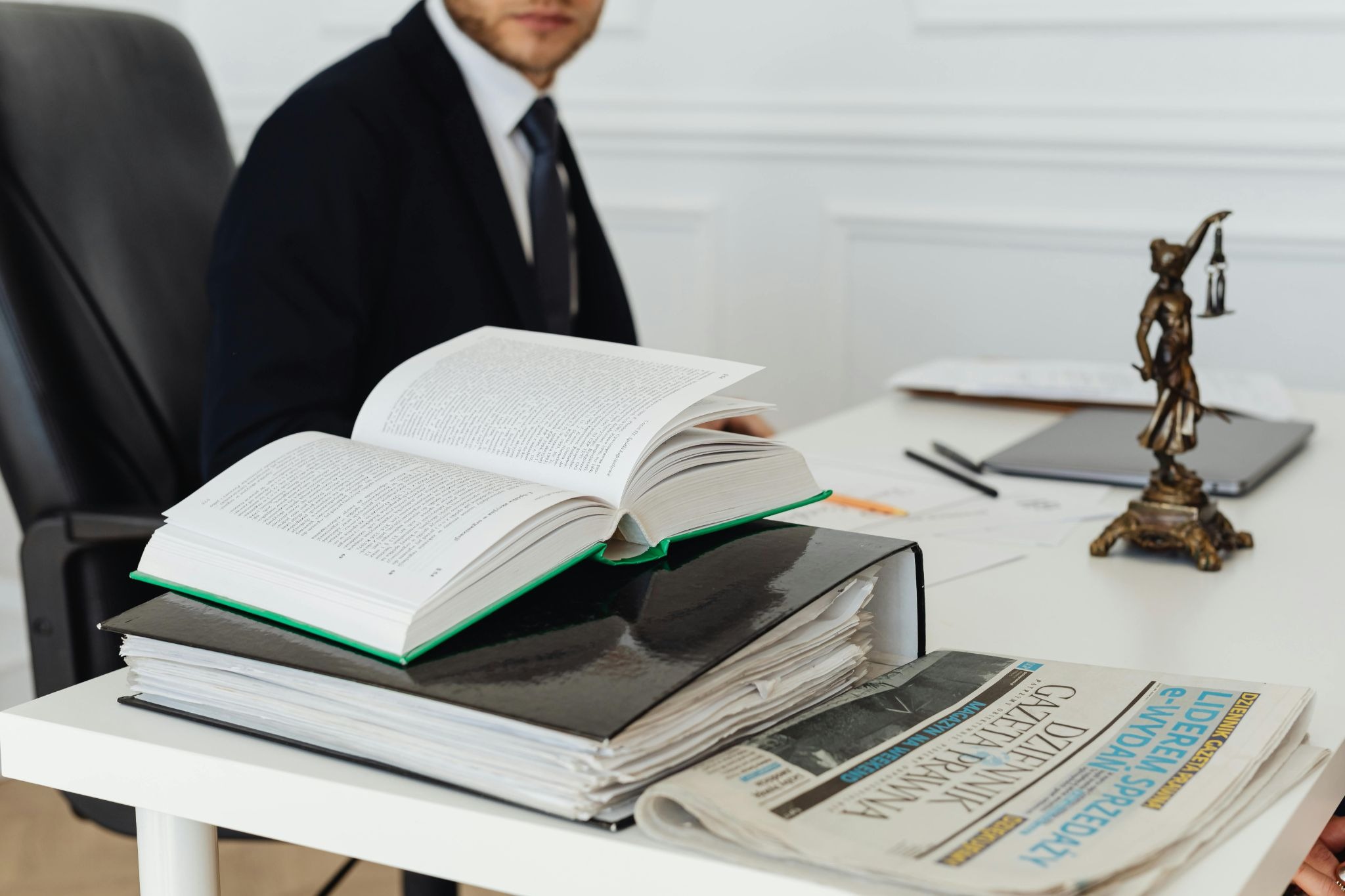 Legal books, documents, and a justice statue on a lawyer’s desk during business law research.