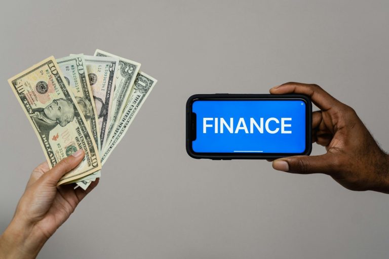 Hands holding cash and a phone with the word finance, representing personal banking choices.