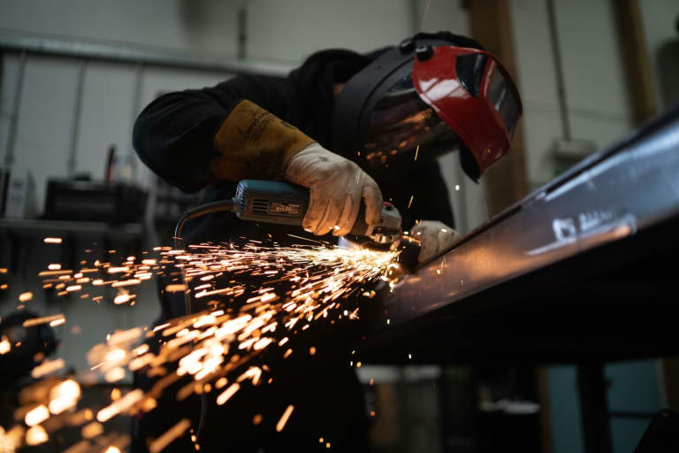 Industrial worker using heavy equipment to cut metal with sparks flying in a workshop