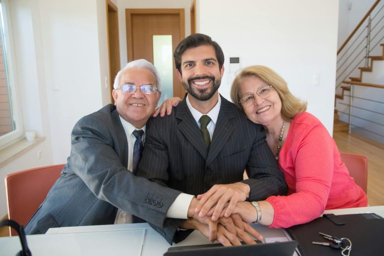 Family business owners smiling together at a meeting table inside a modern office.