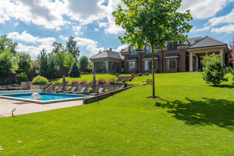 Large backyard with healthy green grass, landscaped garden areas, and a well-maintained lawn surrounding a modern home