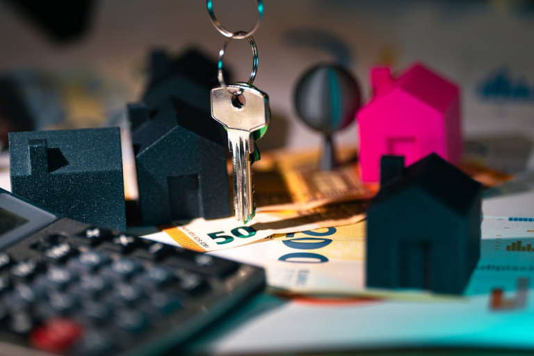 House keys, miniature homes, calculator, and cash representing real estate investments and financial asset protection