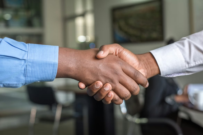 Two people shaking hands in an office to represent business relationships and trust.