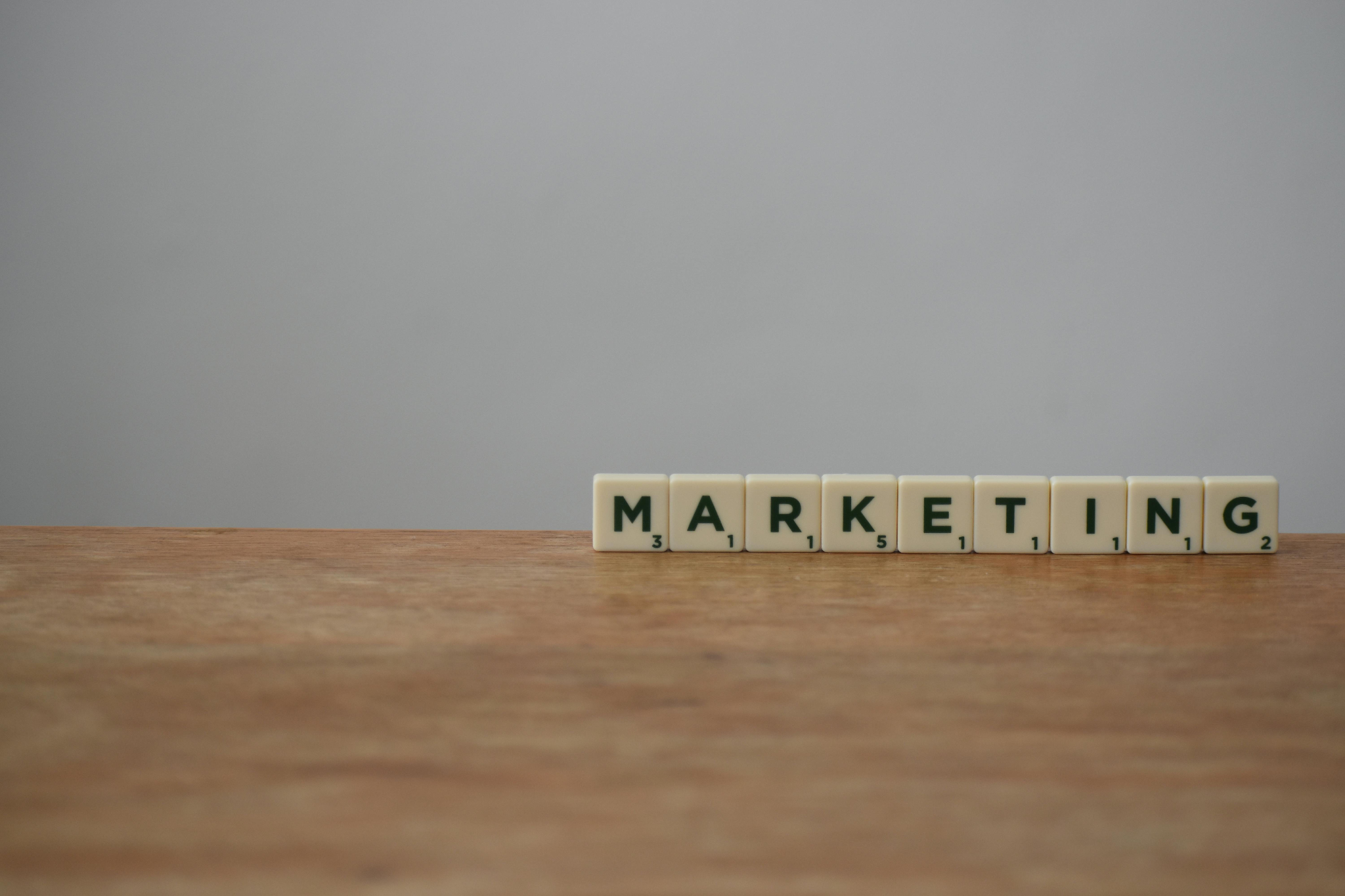 Scrabble tiles spelling the word marketing on a wooden table.