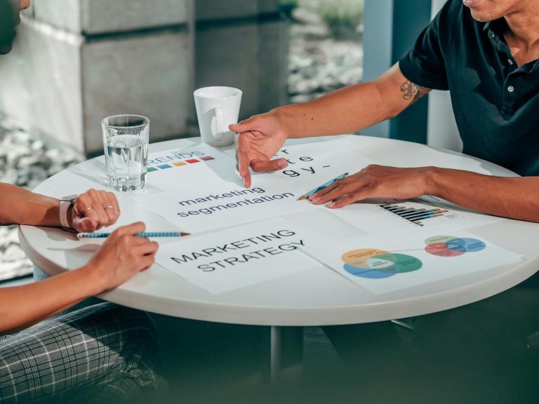 Two people reviewing marketing strategy documents and audience segmentation charts during a business meeting.